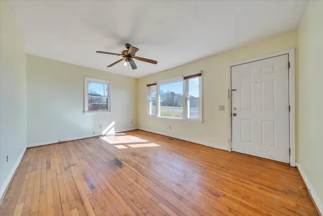a view of an empty room with wooden floor and a window