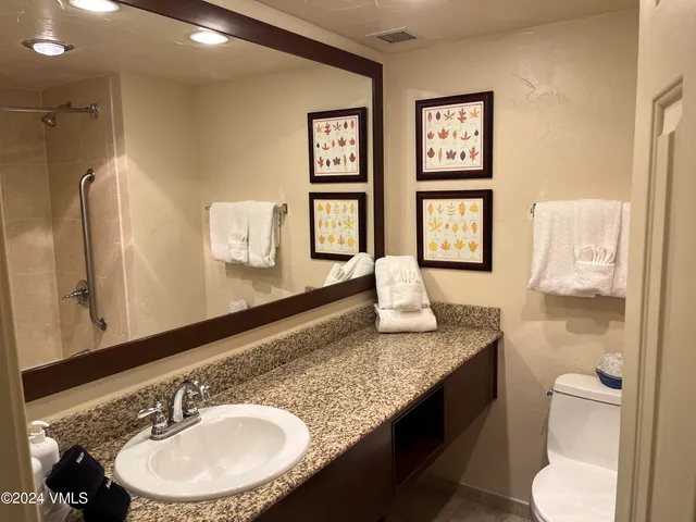 a bathroom with a granite countertop sink toilet and mirror