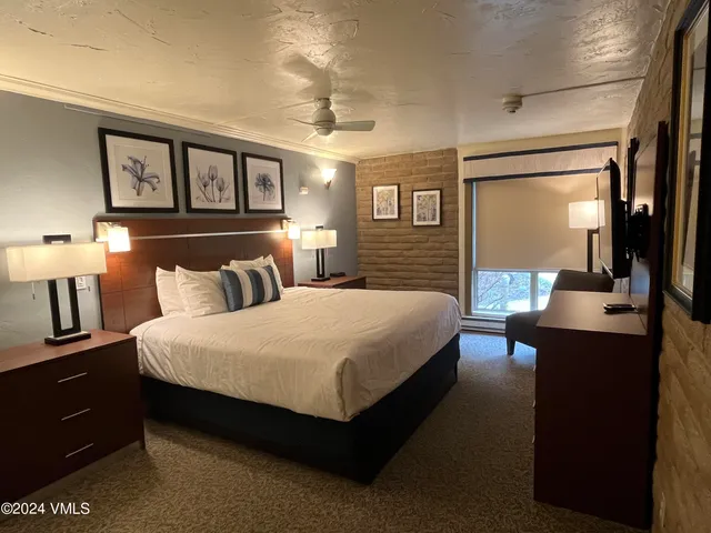 a spacious bedroom with a bed a table and painting on the wall