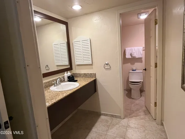 a bathroom with a granite countertop sink mirror and a toilet
