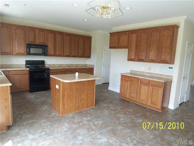 4345 Karlbrook Lane Raleigh, NC 27616 - Photo 3 of 12 a kitchen with stainless steel appliances granite countertop a stove a sink dishwasher and a refrigerator with wooden cabinets