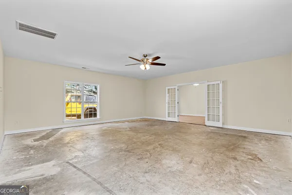 an empty room with windows and fan