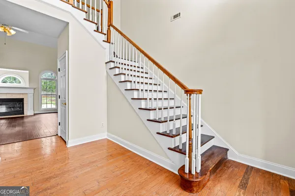 an empty room with wooden floor fan and windows
