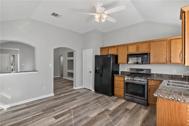 a kitchen with stainless steel appliances granite countertop a refrigerator stove top oven and sink