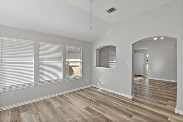 a view of empty room with wooden floor and fan