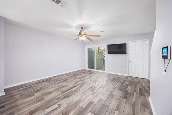 a view of empty room with wooden floor and fan