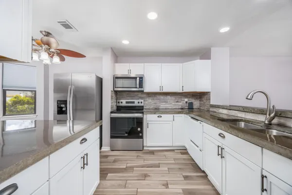 a large kitchen with cabinets a sink and stainless steel appliances