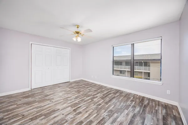 a view of an empty room with a window and wooden floor