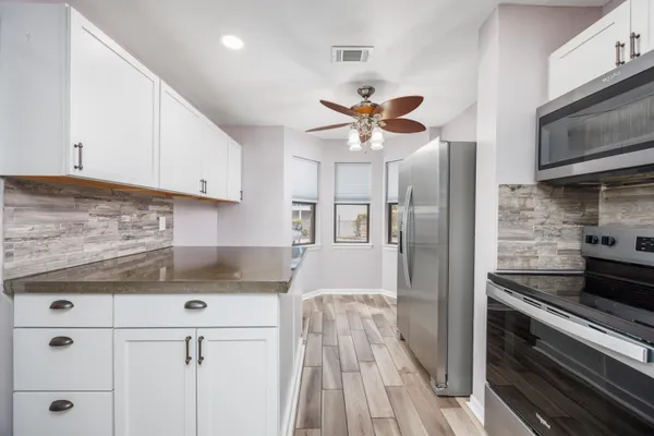 a kitchen with stainless steel appliances granite countertop a refrigerator and a stove top oven