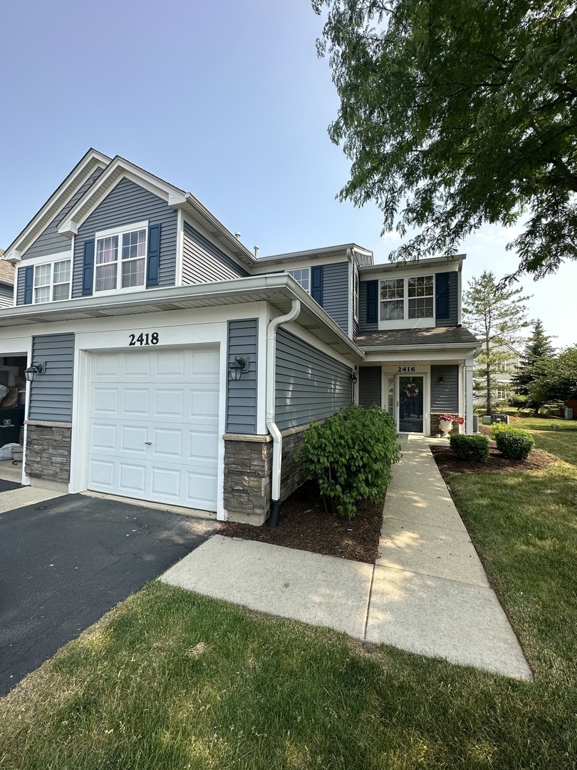 2418 Oneida Lane, Unit 2418 Naperville, IL 60563 - Photo 2 of 15 a front view of a house with a yard and garage