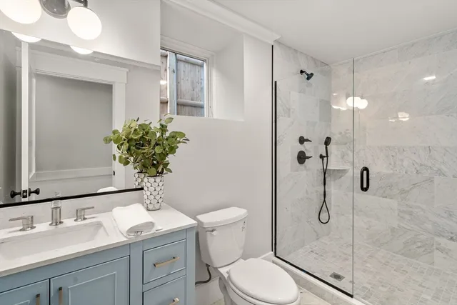 a bathroom with a granite countertop sink a toilet and shower