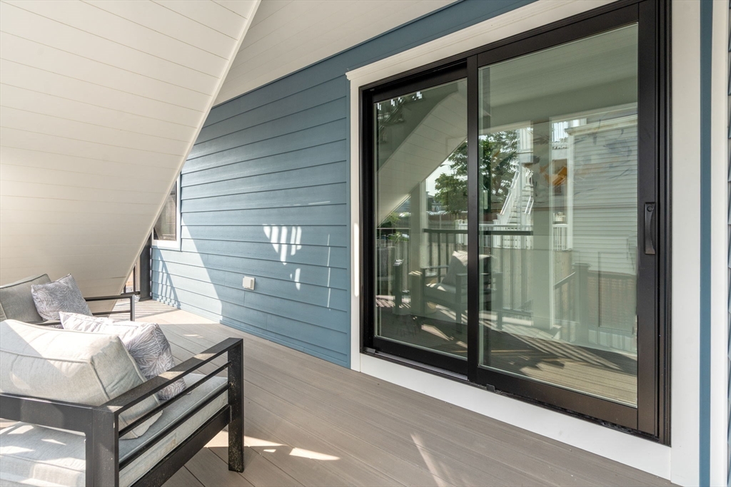 11 Macarthur Street, Unit A Somerville, MA 02145 - Photo 29 of 35 a room with a balcony a bed and glass door