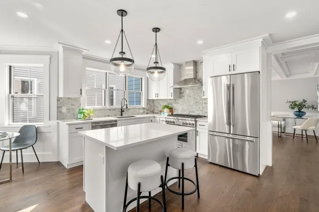 a kitchen with stainless steel appliances granite countertop a refrigerator a sink dishwasher a stove and a dining table with wooden floor