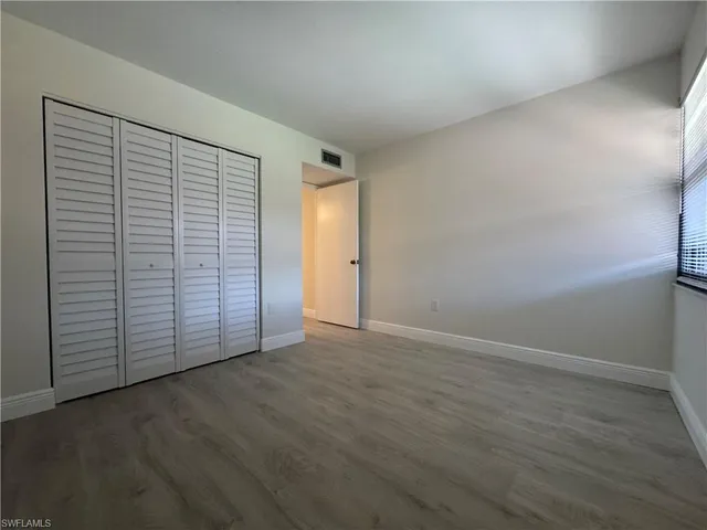 an empty room with wooden floor and closet