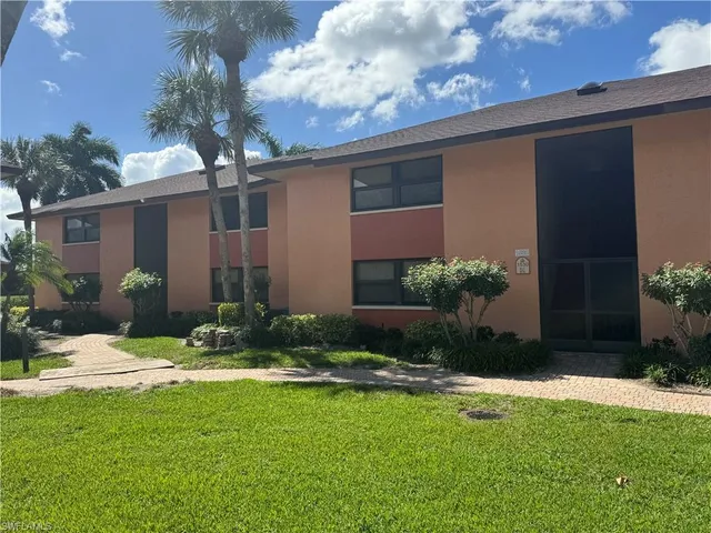 a view of a house with a big yard and palm trees