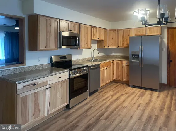 a kitchen with granite countertop a refrigerator stove top oven and sink