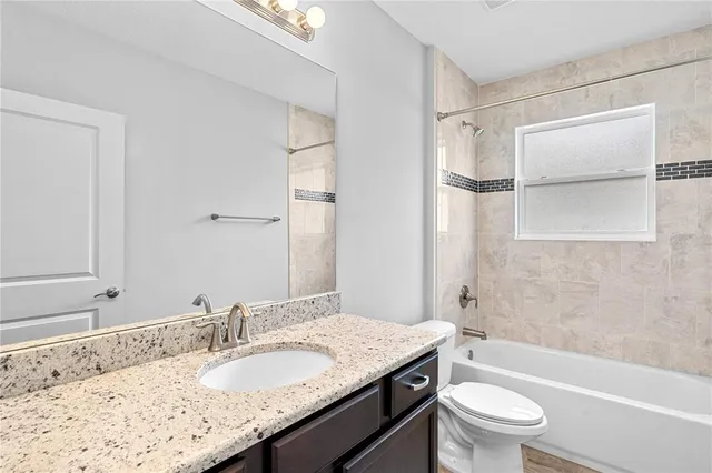 a bathroom with a granite countertop sink a toilet and shower