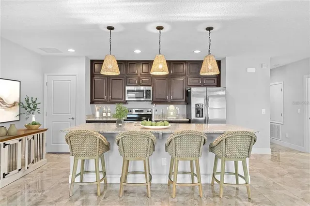a kitchen with stainless steel appliances granite countertop a table chairs and a refrigerator