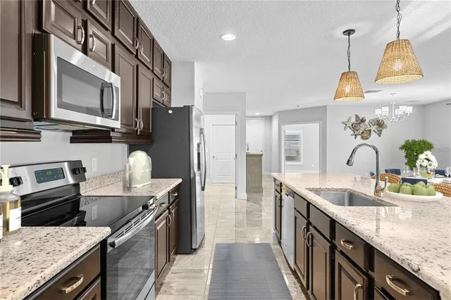 a kitchen with stainless steel appliances granite countertop a sink a stove and a refrigerator