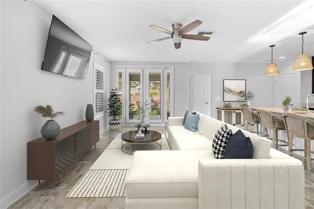 a living room with furniture a ceiling fan a flat screen tv and a large window