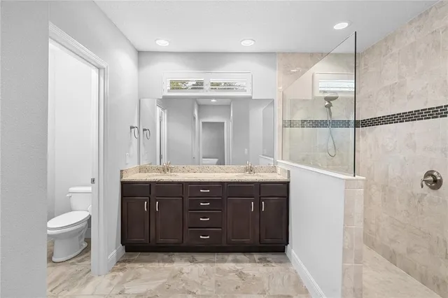 a spacious bathroom with a granite countertop sink a toilet and a shower