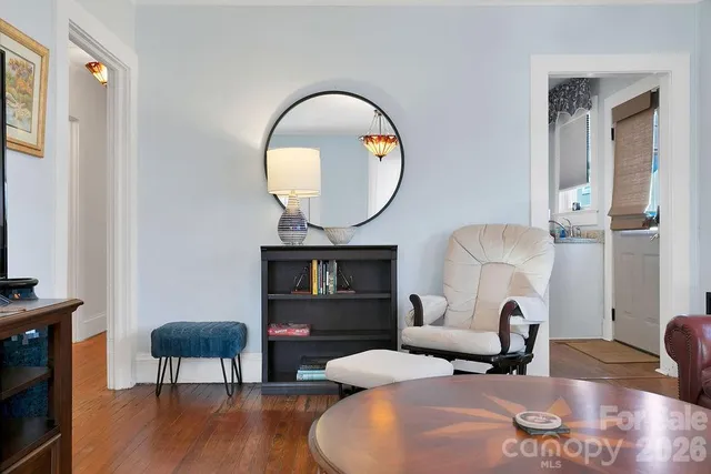 a living room with furniture a mirror and a wooden floor
