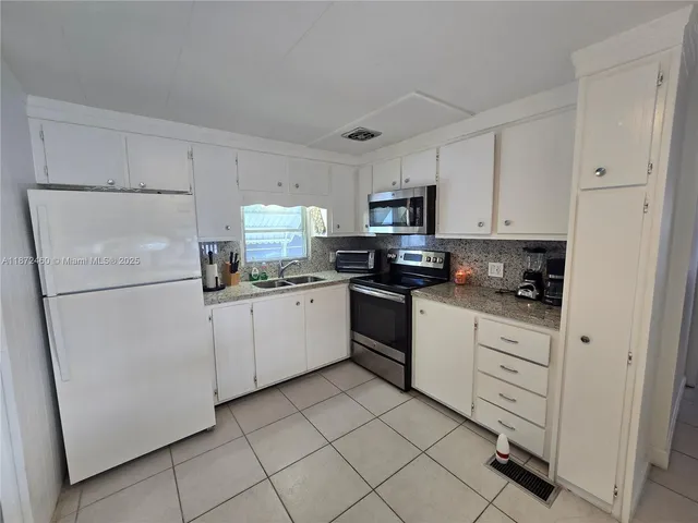 a kitchen with white cabinets stainless steel appliances and a refrigerator