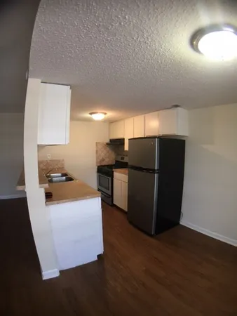 a kitchen with granite countertop a refrigerator and a stove top oven