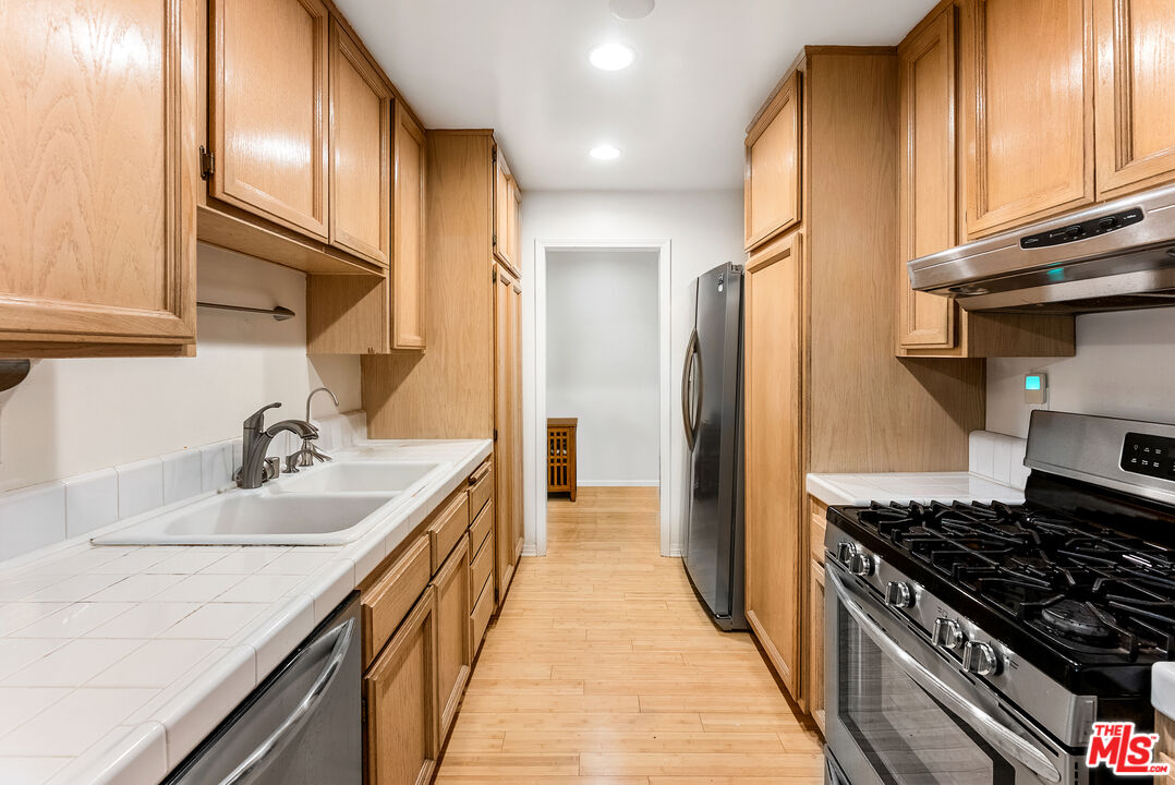 1255 10th Street, Unit 106 Santa Monica, CA 90401 - Photo 5 of 15 a kitchen with kitchen island granite countertop a sink stove and refrigerator