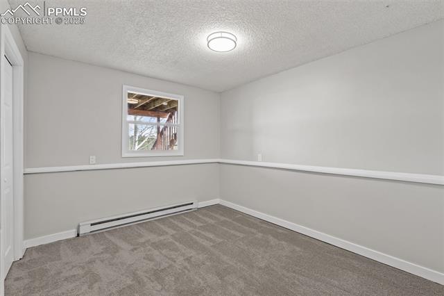 15535 Softwood Road Elbert, CO 80106 - Photo 31 of 47 Unfurnished bedroom featuring baseboard heating, light carpet, and a textured ceiling