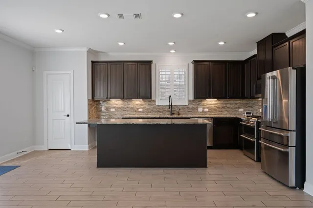 a kitchen with kitchen island granite countertop stainless steel appliances and refrigerator