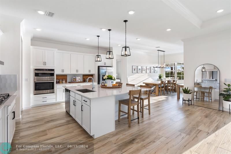 793 Hookline Circle Loxahatchee, FL 33470 - Photo 39 of 80 a kitchen with stainless steel appliances kitchen island granite countertop a stove top oven a sink a dining table and chairs with wooden floor