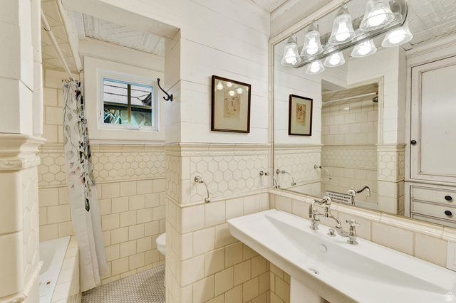 2983 East Ridgetop Road, Unit 27 Provo, UT 84604 - Photo 27 of 63 Classic bathroom featuring subway tile wainscoting, a dual-sink vanity with chrome bridge faucet and vintage-style hardware, large mirror with integrated lighting, and separate shower and toilet compartments
