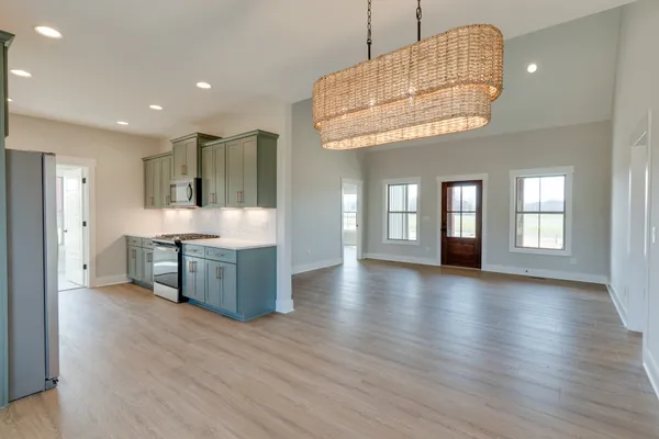 a kitchen with stainless steel appliances granite countertop a refrigerator a sink dishwasher a stove and a dining table with wooden floor