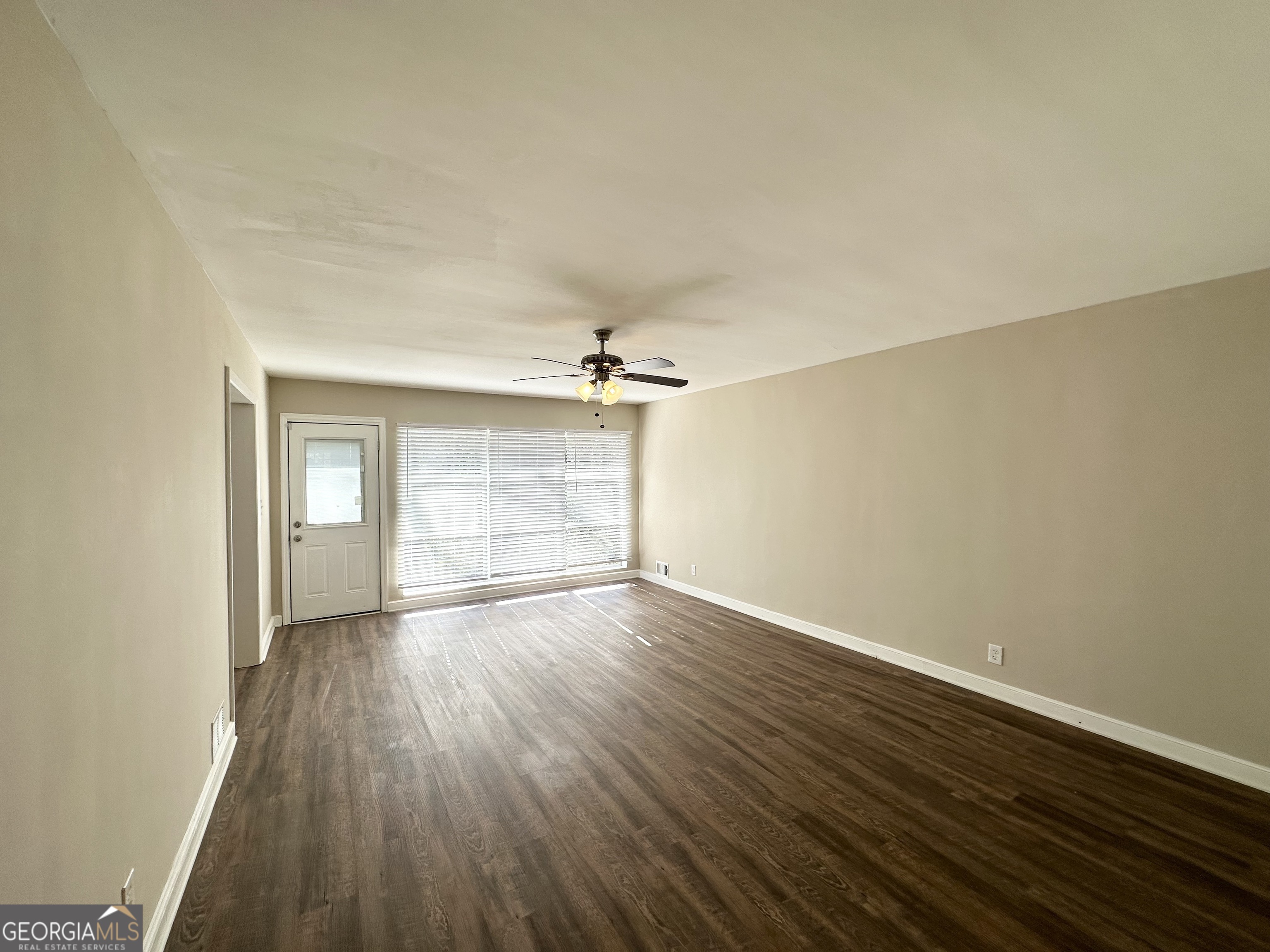 2896 Hogan Road East Point, GA 30344 - Photo 3 of 14 an empty room with wooden floor ceiling fan and windows