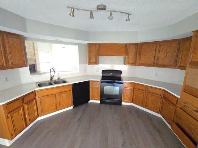 a kitchen with stainless steel appliances a sink a stove a refrigerator cabinets and a window