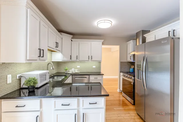 a kitchen with stainless steel appliances granite countertop a sink a stove and a refrigerator