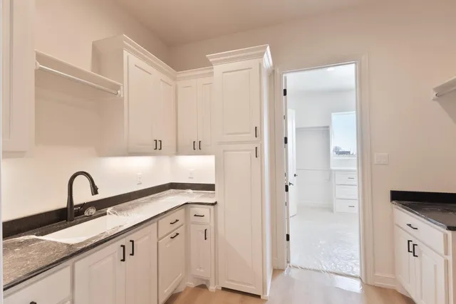 a kitchen with white cabinets and sink