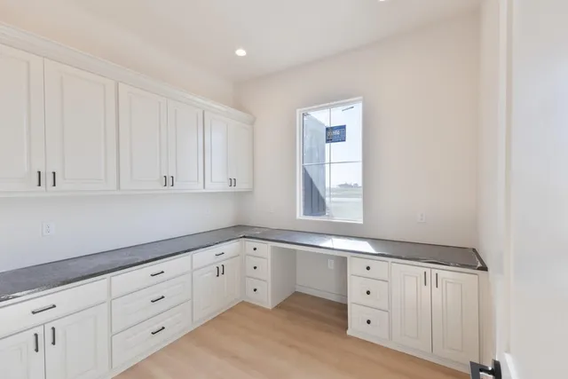 a kitchen with white cabinets and a window