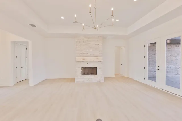 an empty room with a fireplace and chandelier