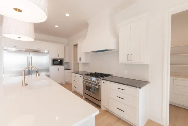 a kitchen with white cabinets and appliances