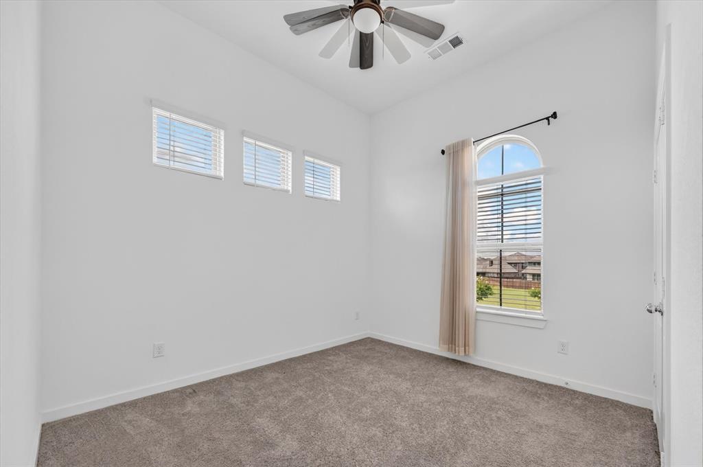 1153 Queensdown Way Forney, TX 75126 - Photo 17 of 26 Carpeted room featuring a ceiling fan with integrated lighting, a high arched window, three rectangular transom windows, and white painted walls