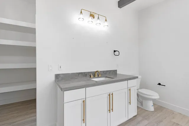 a bathroom with a granite countertop sink a toilet and a mirror