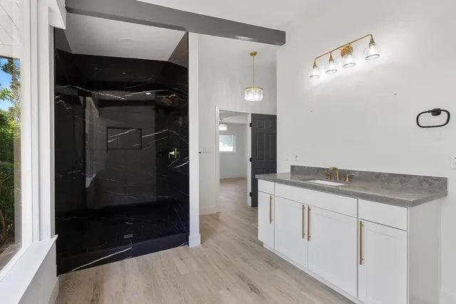 a bathroom with a granite countertop sink a mirror and a shower