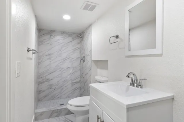 a bathroom with a sink a toilet and shower