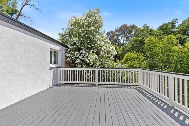a balcony with wooden floor and trees in the background