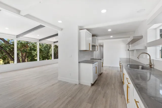 a kitchen with stainless steel appliances granite countertop a sink a stove and a wooden floors