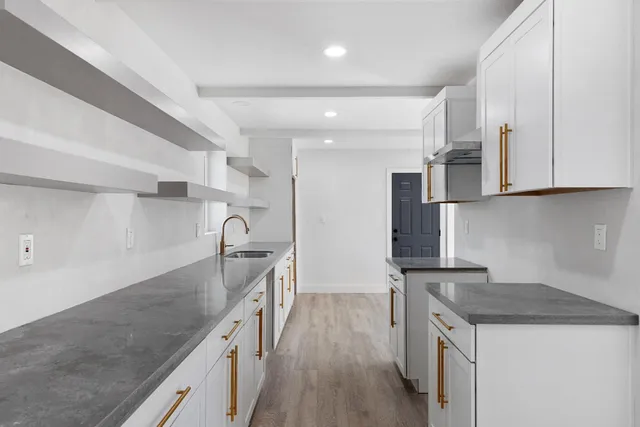 a kitchen with granite countertop a sink a stove and refrigerator