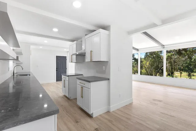 a kitchen with stainless steel appliances granite countertop a stove a sink and a refrigerator with wooden floor