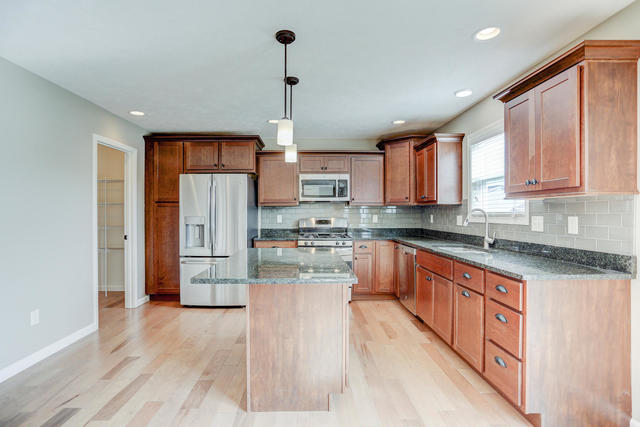 2003 Rylan Road Mahomet, IL 61853 - Photo 7 of 41 a large kitchen with stainless steel appliances kitchen island granite countertop a refrigerator a sink dishwasher a stove and white cabinets with wooden floor